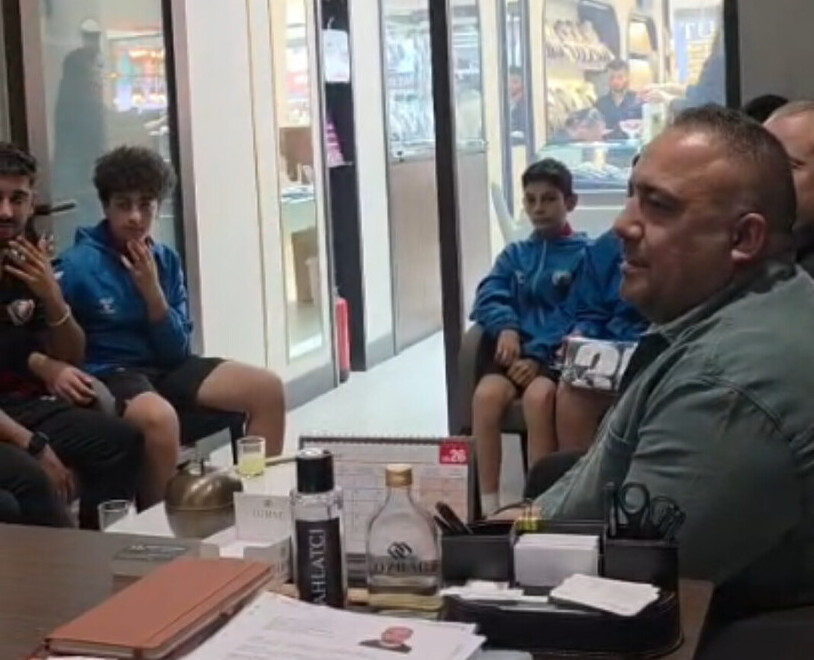 Çiğli Esentepe Spor Antrenörü Uğur Güneş, bir ofis ortamında genç sporcularla birlikte otururken ve konuşurken görülüyor.