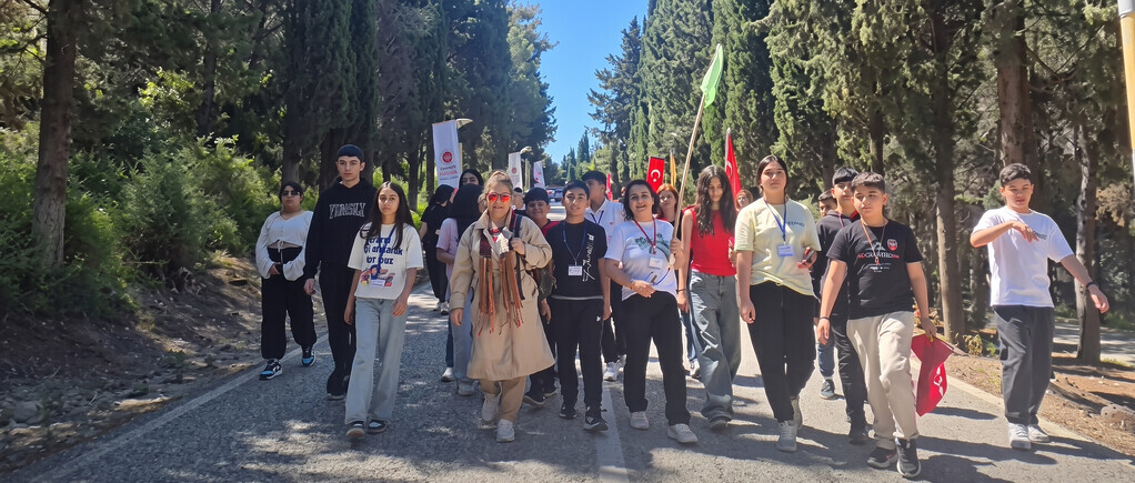 Çiğli Güzeltepe Ortaokulu öğrencileri ve öğretmenleri Çanakkale Şehitliği yolunda bayraklarla yürüyor.