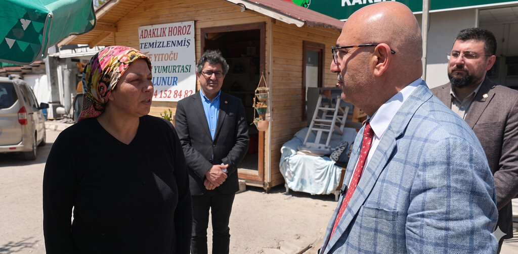 CHP Milletvekili Mahmut Tanal, İzmir Çiğli'nin Kaklıç Mahallesi'nde bir esnaf kadınla sohbet ediyor. Kadın, renkli bir başörtüsü takmış. Arkada, takım elbiseli CHP İzmir İl Yönetim Kurulu Üyesi Barış Ballıkaya ve CHP Çiğli Gençlik Kolları Başkanı Mertcan Eroğlu yer alıyor.