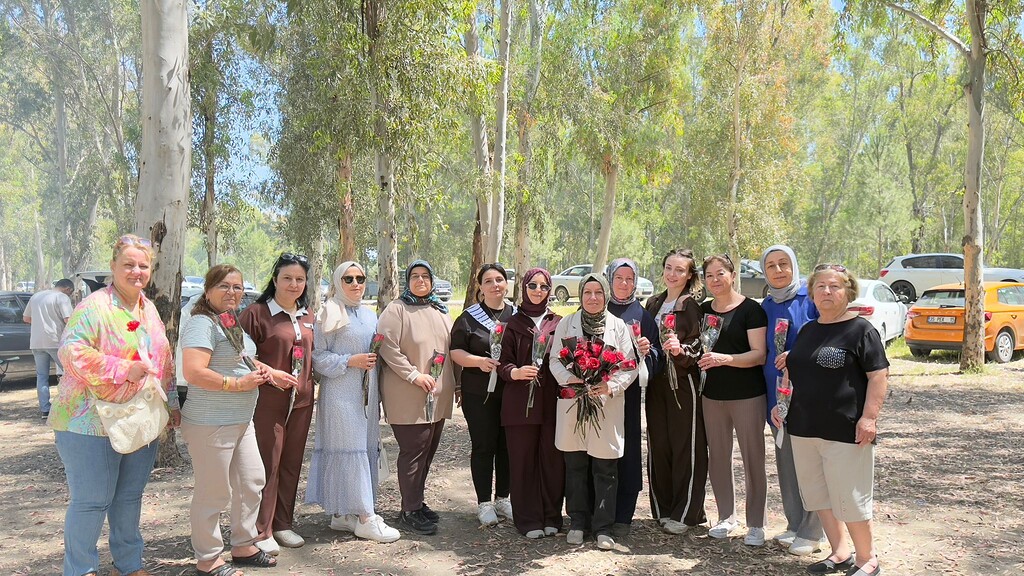 AK Parti Çiğli Kadın Kolları Başkanı Selma Yolcu ve kadın teşkilat üyeleri, Sasalı pikniğinde ellerinde çiçeklerle toplu fotoğraf çekiliyor.