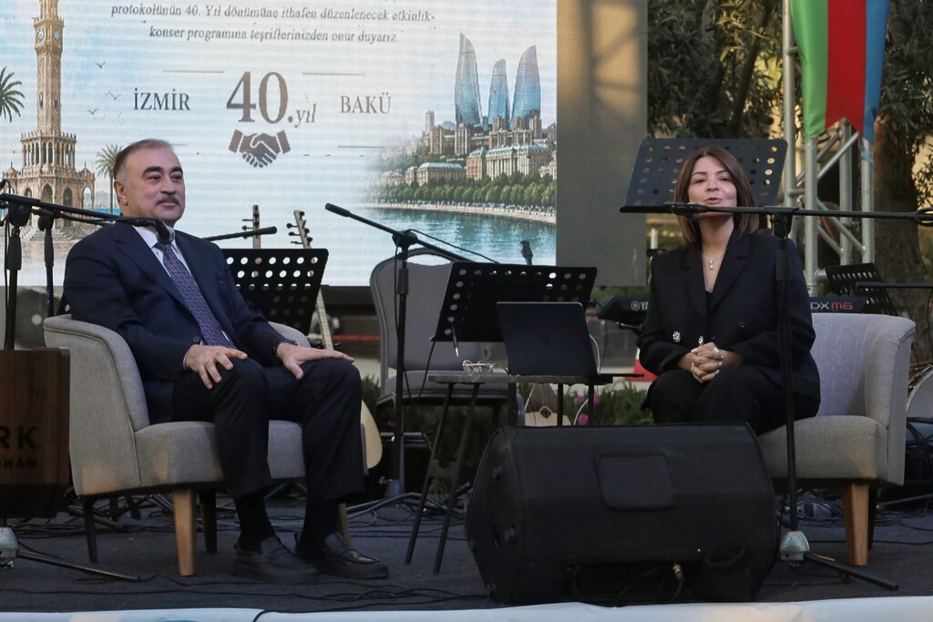 Azerbaycan Türkiye Büyükelçisi Dr. Reşad Memmedov, İzmir-Bakü kardeşliğinin 40. yılı etkinliğinde sahnedeki dijital ekran önünde sunum yaparken.